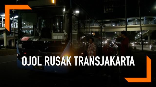 Akibat tersenggol, seorang ojek online emosi dan merusak bus Transjakarta hingga melukai sopir.