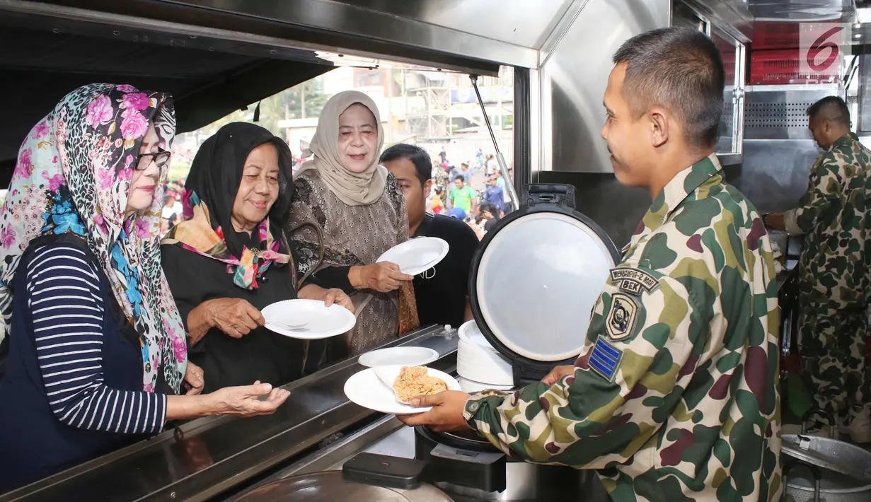 Prajurit Korps Marinir TNI AL memberikan nasi goreng gratis ke warga saat car free day di Jakarta, Minggu (5/11). Kegiatan bagi-bagi nasi goreng ini dalam rangka menyambut HUT Marinir ke-72. (Liputan6.com/Angga Yuniar)
