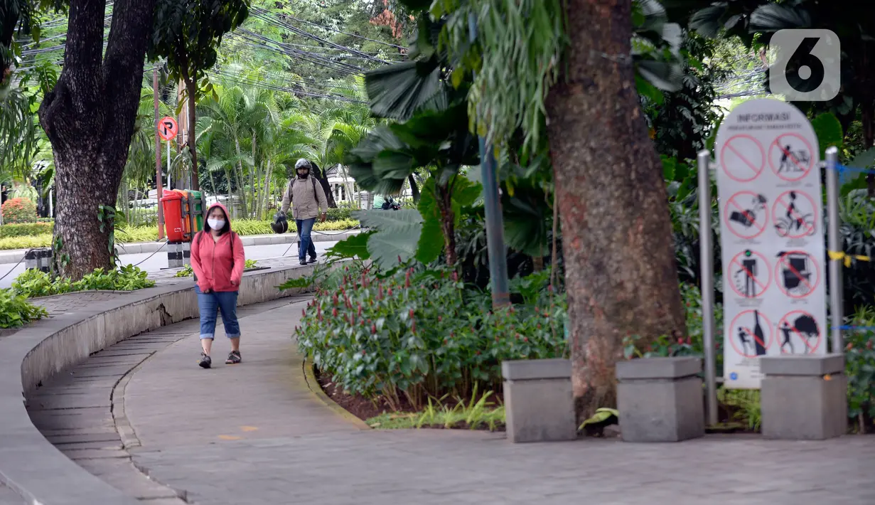 Warga berjalan di Taman Suropati, Menteng, Jakarta, Senin (21/12/2020). Pemerintah Provinsi DKI Jakarta mengeluarkan aturan mengenai pembatasan operasional tempat makan, hiburan, dan lokasi wisata selama libur Natal 2020 dan tahun baru 2021 hingga jam 21.00 malam. (merdeka.com/Dwi Narwoko)