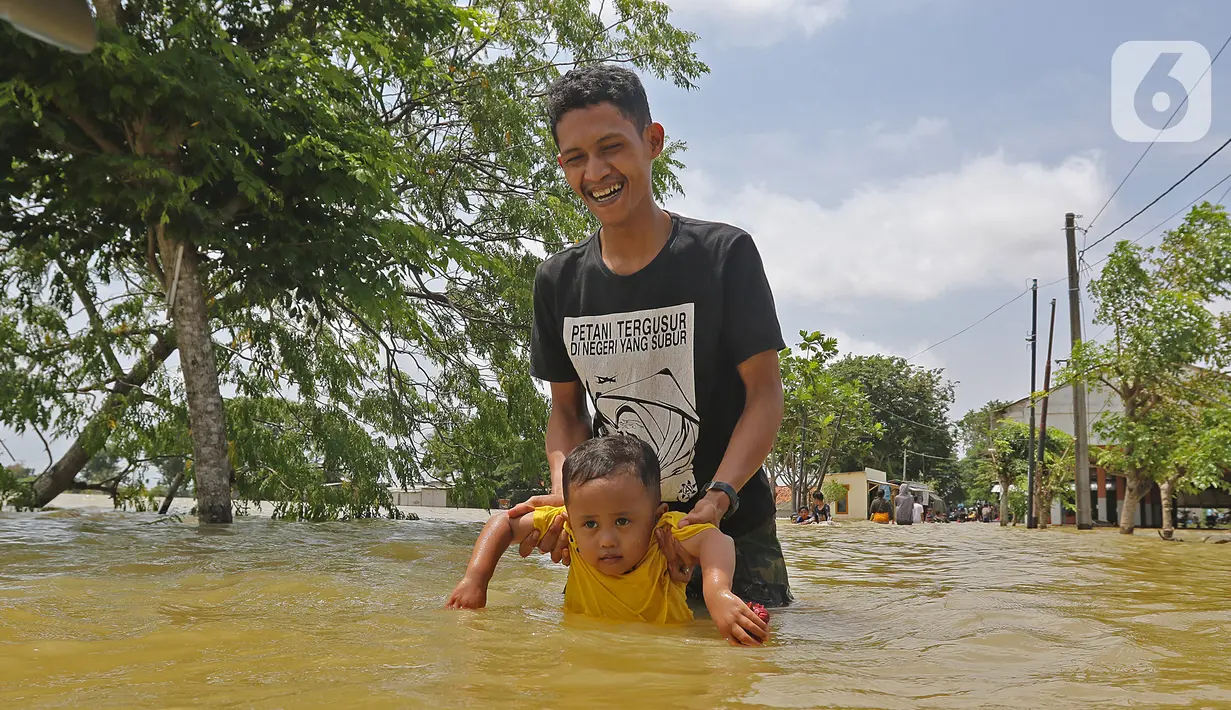 Warga melintasi banjir di Desa Sukalaksana Kabupaten Bekasi, Jawa Barat, Senin (22/02/2021). Jebolnya tanggul Sungai Citarum ini disebabkan oleh debit air yang tinggi. (Liputan6.com/Herman Zakharia)