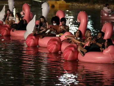 Orang-orang bersantai di atas balon flamingo saat mereka menonton film selama Festival Terapung pertama di Danau Sarah Kubstichek Brasilia, Brasil (30/9/2020). Brasil mengadakan festival pertama yang mengusung tema terapung. (AP Photo/Eraldo Peres)