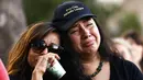 Dua wanita menangis saat menghadiri acara untuk korban penembakan brutal di festival kuliner Gilroy Garlic di Gilroy, California (29/7/2019). Tiga orang tewas dan sedikitnya puluhan orang terluka akibat kejadian tersebut. (AFP Photo/Mario Tama)