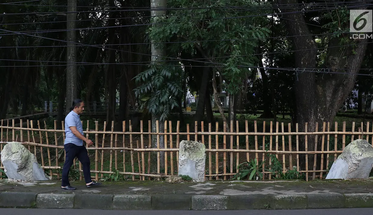 Warga melintas di samping pagar yang ambruk di Taman Hutan Tebet, Jakarta, Kamis (28/3). Kondisi pagar yang ambruk akibat hujan deras tersebut butuh perbaikan karena telah terabaikan selama beberapa bulan terakhir. (Liputan6.com/Immanuel Antonius)