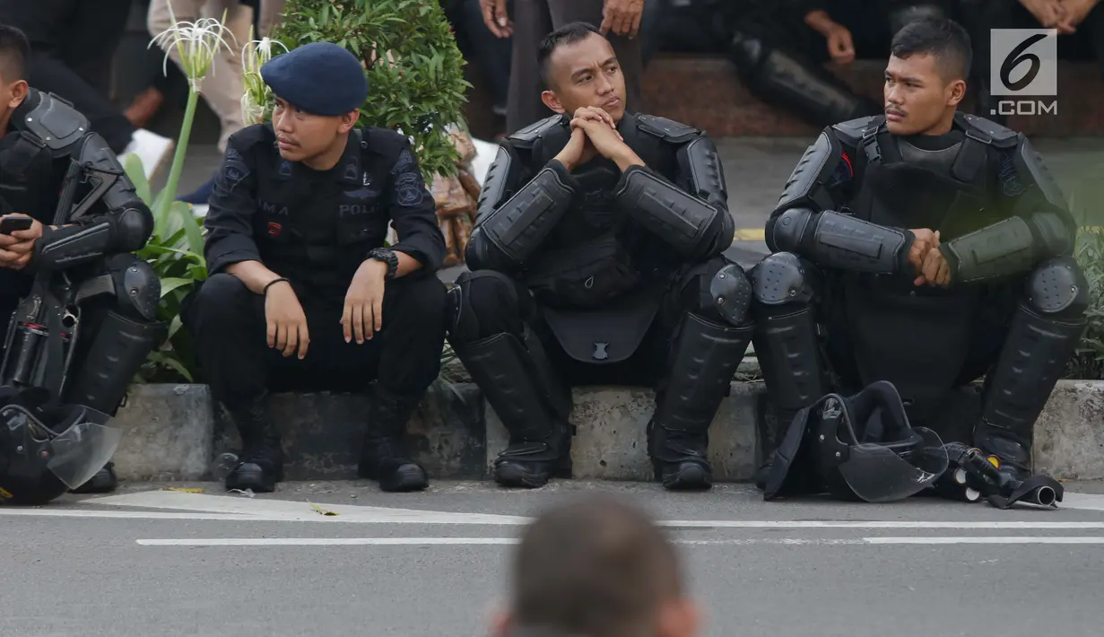 Personil kepolisian dari satuan Brimob beristirahat saat menjaga aksi unjuk rasa yang dilakukan Gerakan Nasional Kedaulatan Rakyat di depan Gedung Bawaslu, Jakarta, Selasa (21/5/2019). Ribuan aparat keamanan gabungan diterjunkan untuk mengamankan jalannya aksi. (Liputan6.com/Helmi Fithriansyah)