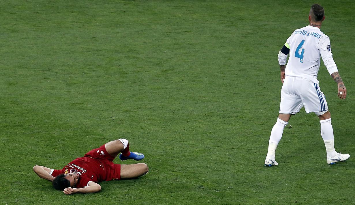Striker Liverpool, Mohamed Salah, terkapar setelah mendapat bantingan dari Sergio Ramos pada laga final Liga Champions di Stadion NSC Olimpiyskiy, Kiev, Minggu (27/5/2018). Salah mengalami cedera bahu usai dilanggar Ramos. (AP/Darko Vojinovic)