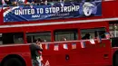 Seorang pria memasang bendera AS mini di bus kampanye menolak Trump di London, Inggris, Rabu (21/9). Mereka mengajak warga AS yang berada di luar negeri untuk tidak memilih Trump sebagai Presiden AS. (REUTERS / Stefan Wermuth)