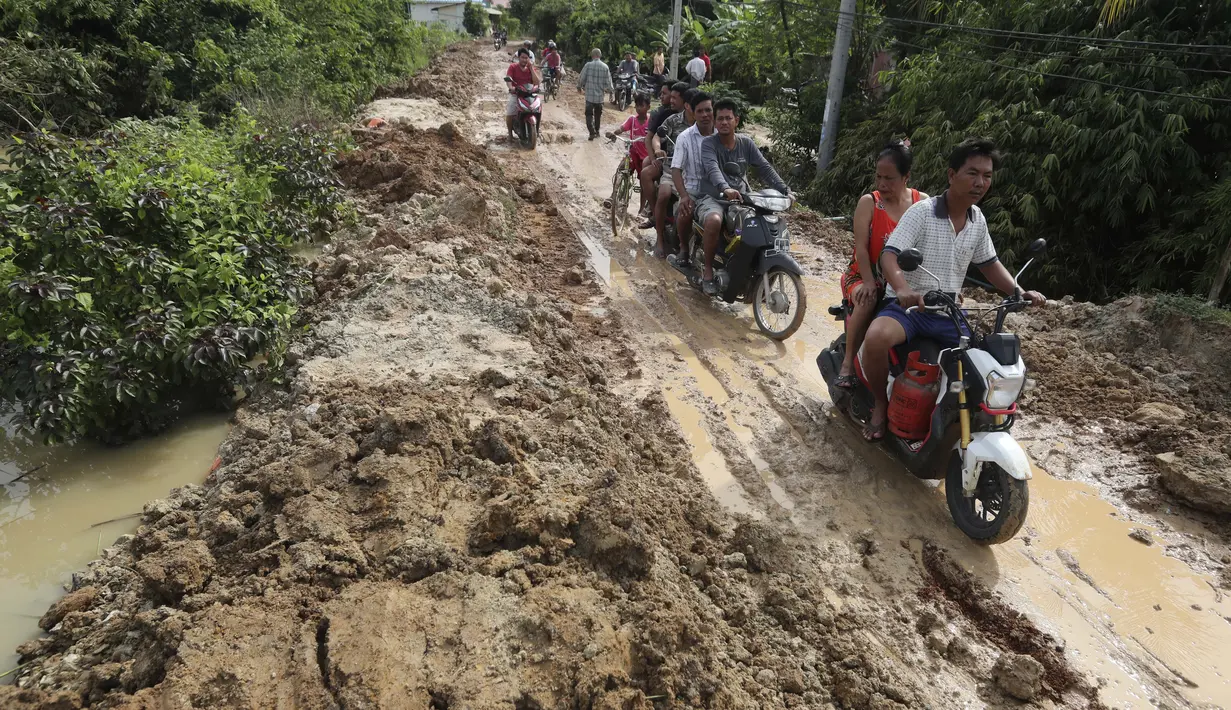 Penduduk desa melakukan perjalanan di dekat bendungan Stung Prek Tnaot setelah banjir menyusul hujan di pinggiran Phnom Penh, Kamboja (14 /10/2020). Pejabat bencana Kamboja mengatakan bahwa lebih dari 10.000 orang telah dievakuasi ke tempat aman setelah badai tropis melanda. (AP Photo/Heng Sinith)
