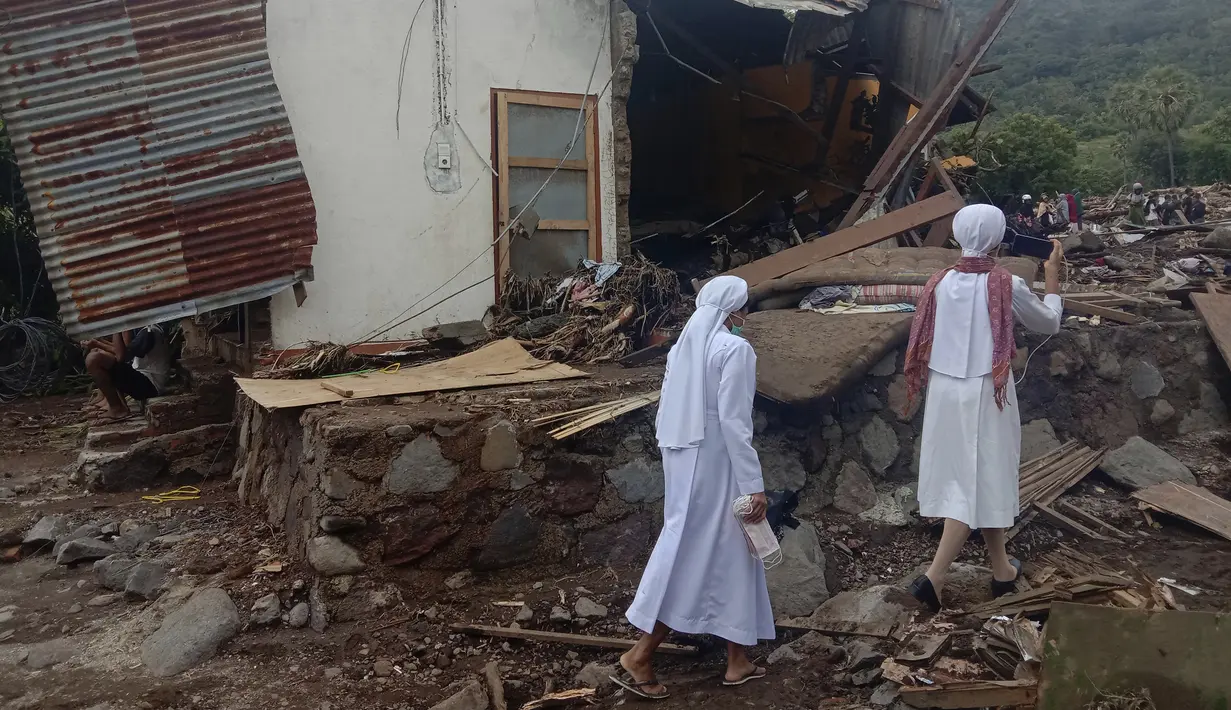 Para biarawati berjalan melewati rumah yang rusak usai banjir bandang di Desa Ile Ape, Pulau Lembata, Nusa Tenggara Timur, Selasa (6/4/2021). Tim penyelamat terus menggali puing tanah longsor untuk mencari korban yang terkubur usai bencana banjir bandang. (AP Photo/Ricko Wawo)