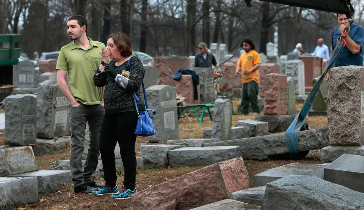 Sally Amon dan anaknya Max Amon saat melihat batu nisan neneknya yang dirusak usai mendapatkan serangan vandalisme di Chesed Shel Emeth Cemetery di University City, St Louis, Missouri, (21/2). (Robert Cohen /St. Louis Post-Dispatch via AP)