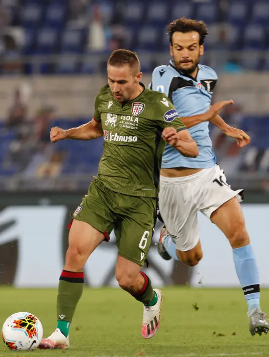 Pemain Cagliari, Marko Rog membawa bola dari kejaran bek Lazio, Marco Parolo pada pertandingan lanjutan Liga Serie A Italia di Stadion Olimpiade Roma, di Roma, Italia, Kamis, (23/7/2020). Lazio menang 2-1 atas Cagliari. (AP Photo/Riccardo De Luca)
