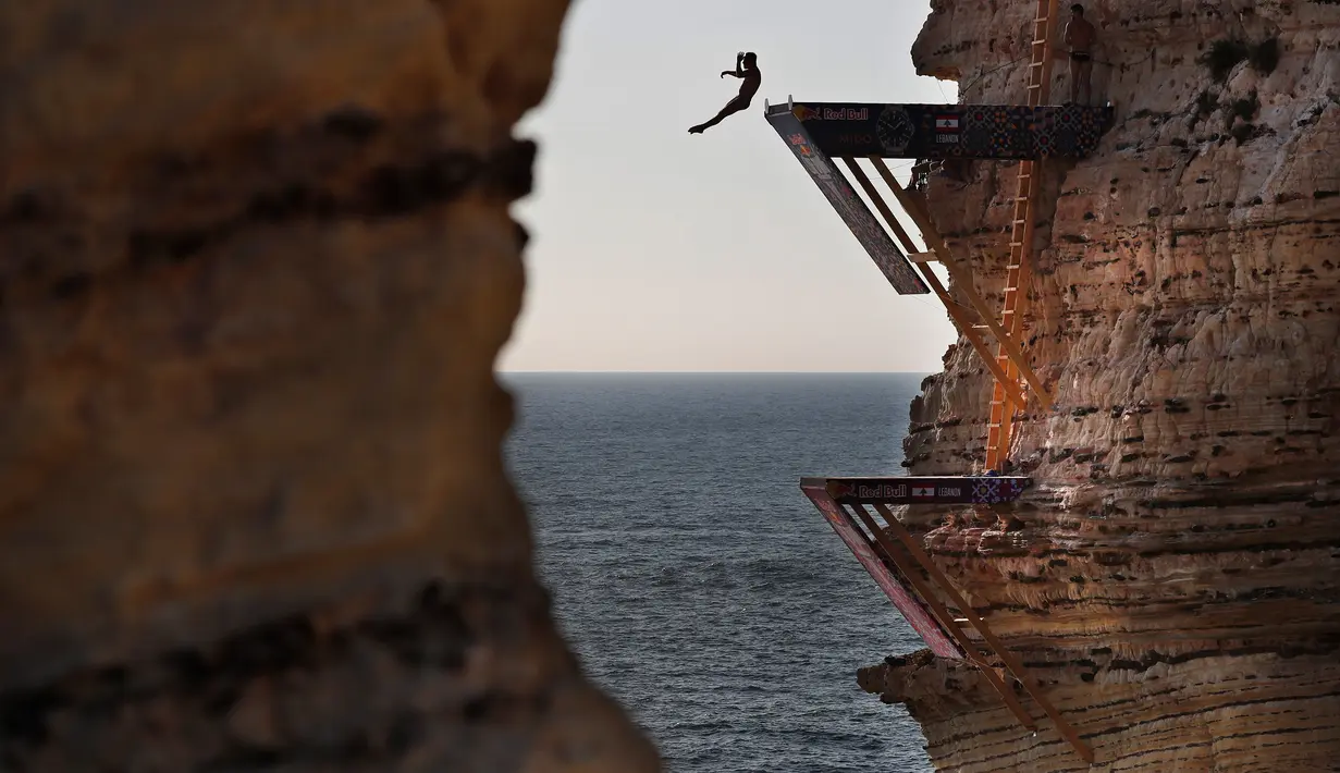 Peserta melompat dari batu karang laut 'Raouche' yang terkenal dalam kompetisi Red Bull Cliff Diving World Series di Beirut, Lebanon, 14 Juli 2019. Sebanyak 40 atlet terdiri dari 10 wanita dan 14 pria yang berasal dari 18 negara melakukan lompatan dari ketinggian 21 - 27 meter. (AP/Hussein Malla)