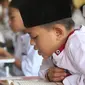 Santri yang masih berusia belasan tahun membaca Al Quran bersama-sama (tadarus) dalam rangka mengkhatamkan Qur'an dengan menerapkan jaga jarak pada Masjid Daarul Qu'ran  Pesantren Al Kautsar, Cibinong, Bogor, Jawa Barat, Minggu (10/04/2022). (merdeka.com/Arie Basuki)