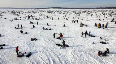 Pemancing di dekat lubang pemancingan saat Brainerd Jaycees Ice Fishing Extravaganza tahunan ke-32 di Gull Lake's Hole di Teluk Day, Minnesota pada 29 Januari 2022. Hampir 10.000 pemancing dari Minnesota dan negara bagian lain menghadiri kontes memancing es amal terbesar di dunia. (Kerem Yucel/AFP)