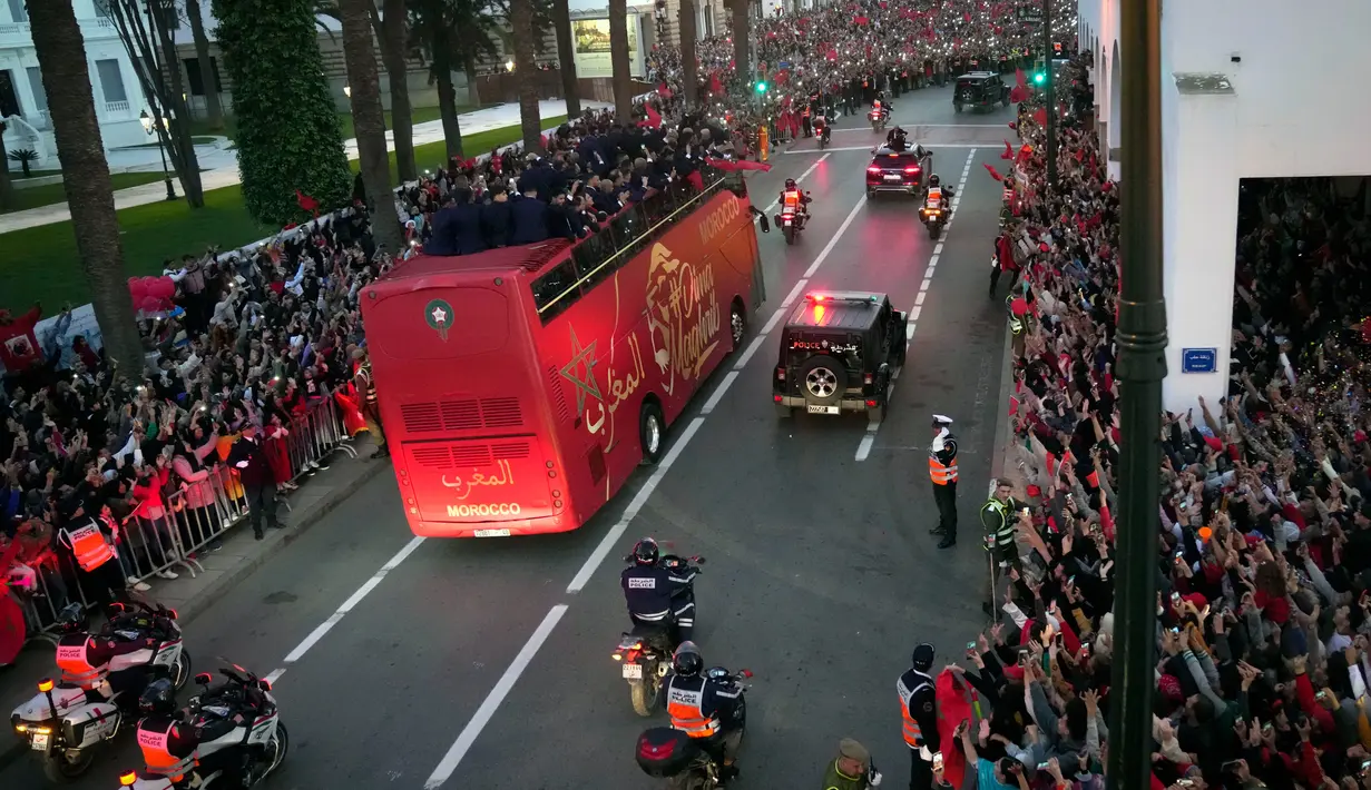<p>Para pemain Timnas Maroko melakukan selebrasi di atas bus dan melambaikan tangan ke publik saat parade di Rabat , Maroko, 20 Desember 2022. Timnas Maroko mendapat sambutan hangat di negaranya setelah berhasil meraih juara keempat Piala Dunia 2022. (AP Photo/Mosa'ab Elshamy)</p>