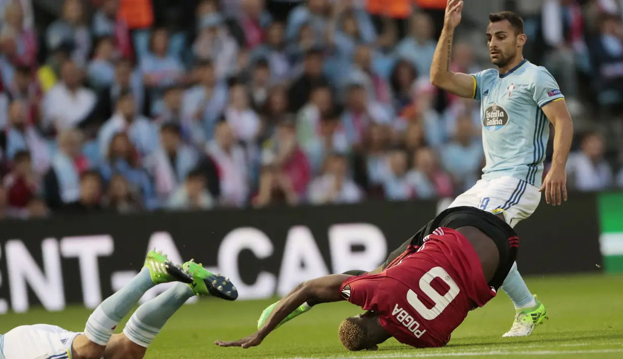 Pemain Manchester United, Paul Pogba terjatuh saat berebut bola dengan para pemain Celta Vigo pada leg pertama semifinal Liga Europa di Balaidos stadium, Vigo, (4/5/2017). MU menang 1-0. (AP/Lalo R. Villar)