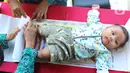 Petugas menimbang bayi saat Bulan Imunisasi Anak Nasional di RPTRA Pola Idaman, Pondok Labu, Jakarta Selatan, Senin (1/8/2022). Sebanyak 76 anak mengikuti bulan imunisasi anak nasional pemberian imunisasi tambahan Campak-Rubela dan pemberian imunisasi pada anak yang belum mendapatkan imunisasi lengkap. (Liputan6.com/Herman Zakharia)