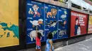 Anak-anak belajar jenis-jenis hewan melalui gambar mural di Jalan Pademangan 2, Jakarta, Senin (18/11/2019). Pembuatan Mural edukasi ini bertujuan memberikan edukasi positif kepada anak-anak di sekitar kawasan itu. (Liputan6.com/Faizal Fanani)