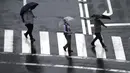 Orang-orang berjalan di tengah hujan saat Topan Mindulle di Tokyo, Jepang, Jumat (1/10/2021). Topan Mindulle sedang bergerak di lepas pantai Jepang. (AP Photo/Eugene Hoshiko)