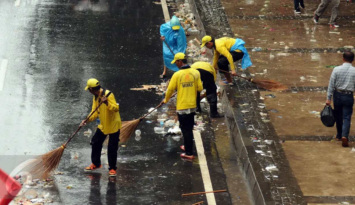 Petugas kebersihan menyapu jalan Medan Merdeka Barat yang dipenuhi sampah usai perayaan hari Buruh Internasional, Jakarta, Senin (5/1). Ribuan massa buruh ikut dalam perayaan Hari Buruh Internasional 2017. (Liputan6.com/Helmi Fithriansyah)