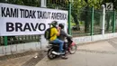 Kendaraan melintas di depan spanduk bertulisan "Kami Tidak Takut Amerika Bravo TNI" terpampang di pagar Stasiun Gambir, Jakarta, Senin (23/10). Pemasangan spanduk ini diduga terkait undangan Panglima TNI yang ditolak masuk AS. (Liputan6.com/Faizal Fanani)