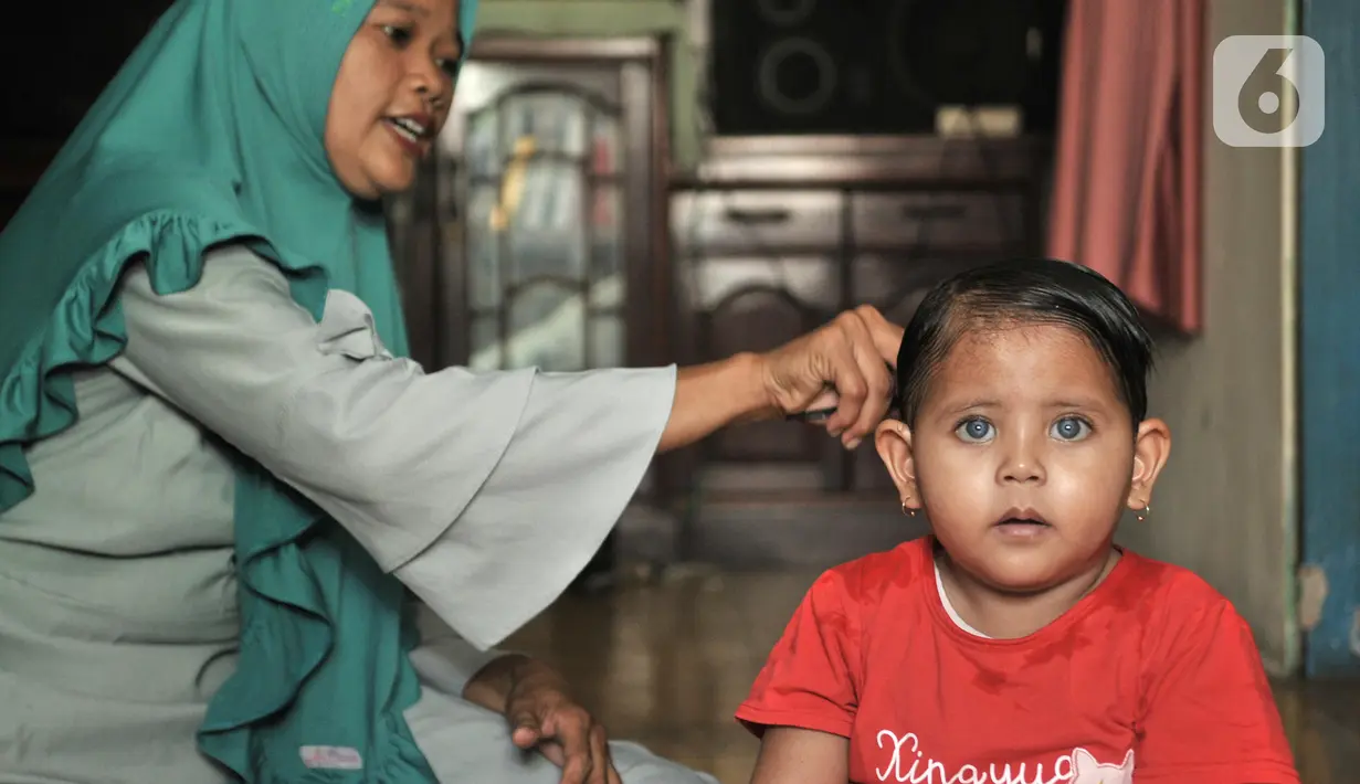 Fauziah Afiqa (kanan) disisiri neneknya di kediamannya di Kampung Bulak Sentul, Harapan Jaya, Bekasi, Jawa Barat, Kamis (10/10/2019). Menurut pengakuan keluarga, mata Afiqa sensitif dengan cahaya yang berlebihan. (merdeka.com/Iqbal Nugroho)