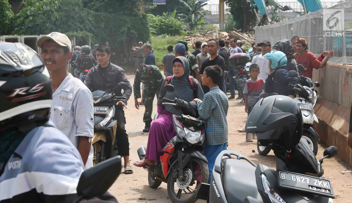 Warga berkerumun menyaksikan eksekusi bangunan rumah milik warga yang terdampak proyek Jalan Tol Cijago di kawasan Kukusan, Depok, Jawa Barat, Rabu (12/12). Di Kukusan, PN Depok kembali mengeksekusi 20 bidang lahan. (Liputan6.com/Immanuel Antonius)