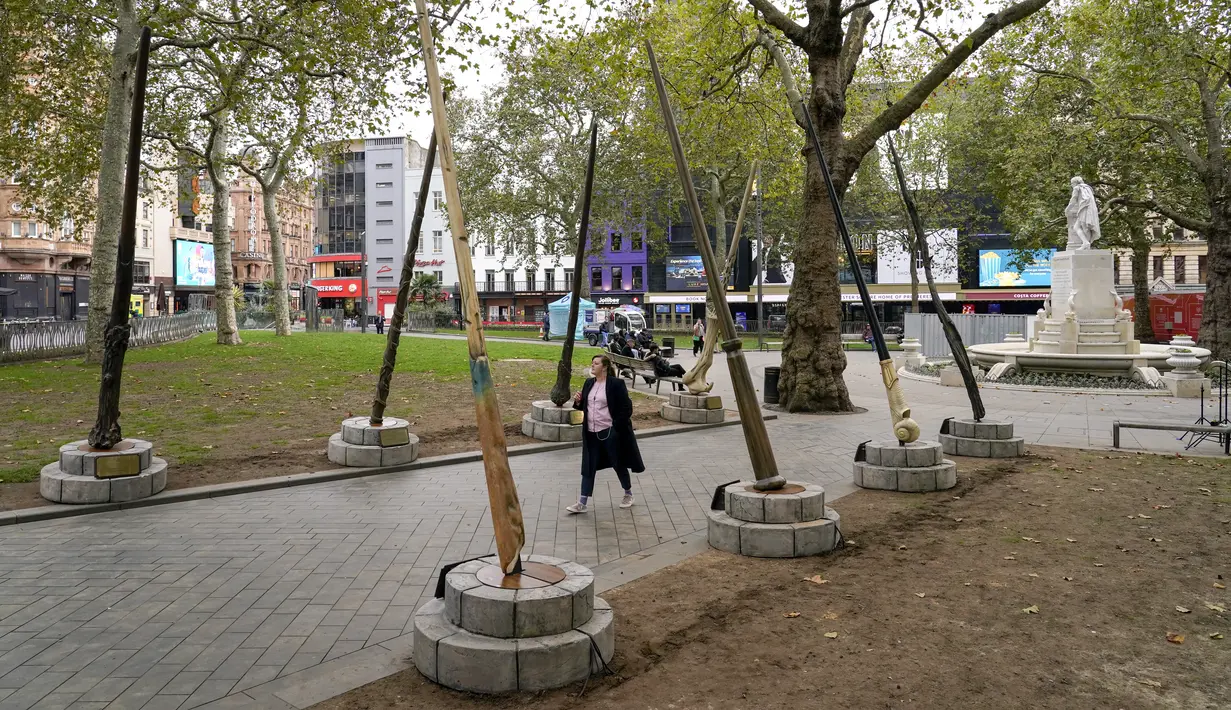 Orang-orang berjalan di bawah tongkat raksasa untuk peringatan 20 tahun film Harry Potter and the Philosopher's Stone di Leicester Square, London, Rabu (13/10/2021). Instalasi terdiri dari sembilan tongkat setinggi 15 kaki yang mewakili sembilan karakter kunci dari film. (AP Photo/Alberto Pezzali)