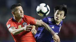 Gelandang Chili, Charles Aranguiz, duel udara dengan gelandang Jepang, Shoya Nakajima, pada laga Copa America 2019 di Stadion Morumbi, Selasa (18/7). Chili menang 4-0 atas Jepang. (AP/Andre Penner)