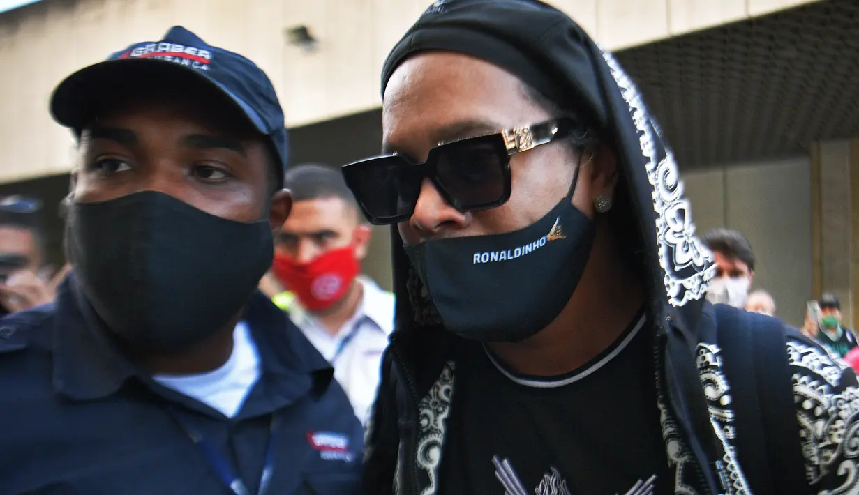 Mantan pemain timnas Brasil, Ronaldinho tiba di bandara El Galeao di Rio de Janeiro, setelah menjalani tahanan rumah di Paraguay, Selasa (25/8/2020). Pria 40 tahun itu sendiri yang mengumumkan hasil tes yang positif Covid-19 di akun Instagram-nya. (AFP/Carl dE Souza)
