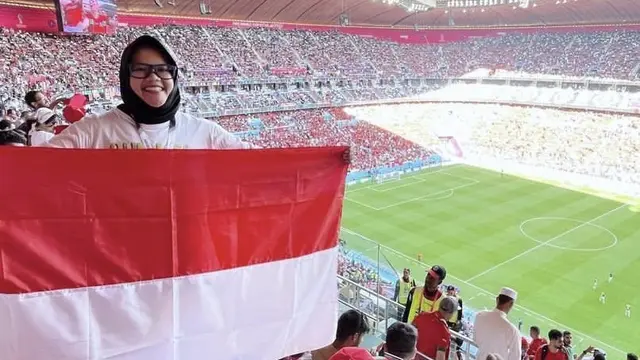 Mita membentangkan bendera Indonesia di Stadion pertandingan Piala Dunia 2022