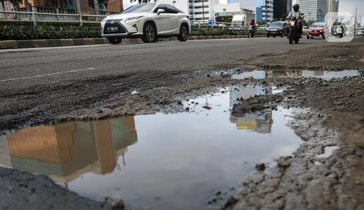 Sejumlah pengendara saat melintas dekat jalan yang berlubang di kawasan Gatot Subroto, Jakarta, Kamis (18/11/2021). Memasuki musim hujan yang turun hampir setiap hari membuat sejumlah ruas jalan rusak dan tergenang sehingga mengakibatkan jalan berlubang. (Liputan6.com/Johan Tallo)