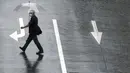 Seorang pria menyeberang jalan di tengah hujan dari Topan Mindulle di Tokyo, Jepang, Jumat (1/10/2021). Topan Mindulle sedang bergerak di lepas pantai Jepang. (AP Photo/Eugene Hoshiko)