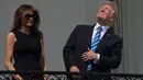 Presiden AS Donald Trump bersama Ibu Negara, Melania Trump menyaksikan fenomena langka gerhana matahari dari balkon Gedung Putih di Washington, Senin (21/8). Trump tampak menatap langsung ke arah matahari dengan mata telanjang. (NICHOLAS KAMM/AFP)