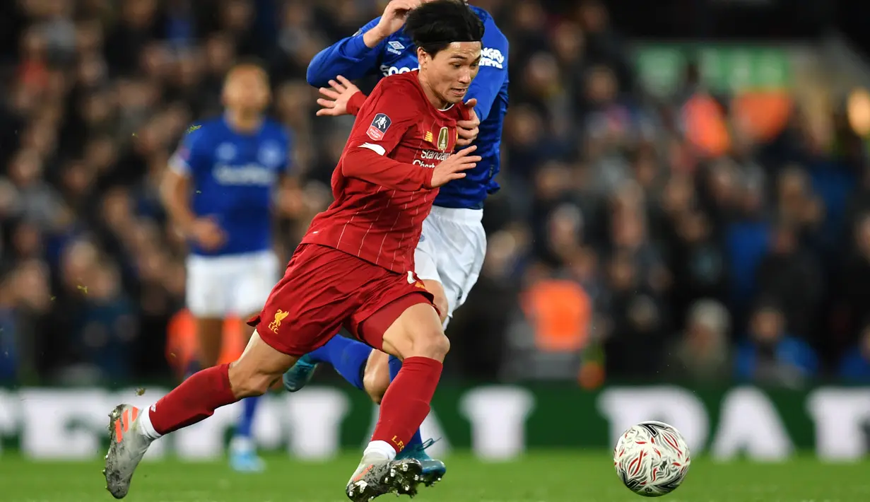 Gelandang Liverpool, Takumi Minamino menggiring bola dari kawalan pemain Everton, Gylfi Sigurdsson pada pertandingan babak ketiga Piala FA di Anfield, Minggu (5/1/2020). Pemain Jepang menjalani debut bersama Liverpool dengan menjadi starter dipertandingan tersebut. (AFP/Paul Ellis)