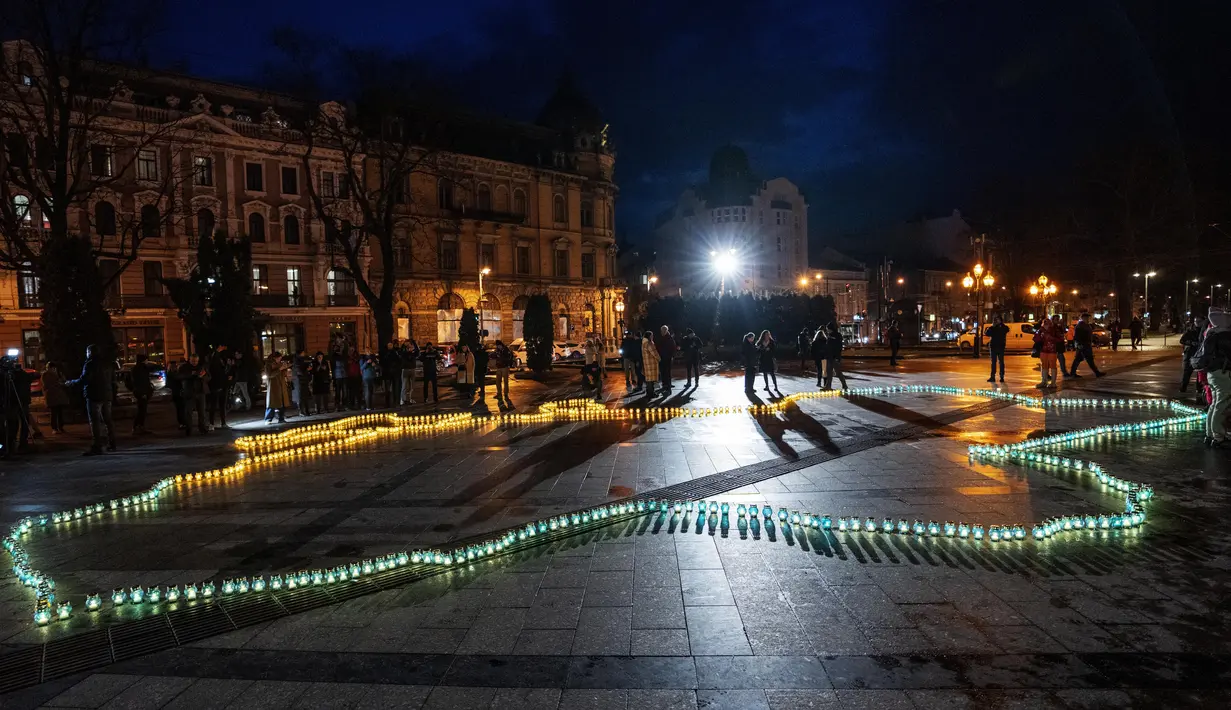 Orang-orang menyalakan lilin membentuk peta Ukraina, untuk mengenang nyawa yang hilang, di depan monumen Taras Shevchenko, di Lviv, Ukraina barat, Selasa malam (5/4/2022). Warga Ukraina berkumpul untuk momen menghormati nyawa yang hilang dalam perang. (AP Photo/Nariman El- Mofty)