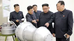 Kim Jong-un berbincang dengan para peneliti saat meninjau pembuatan bom hidrogen pada 3 September 2017. Bom ini diklaim berkekuatan hingga ratusan kiloton ini dibuat dengan berbagai komponen produksi dalam negeri. (AFP Photo/Kcna Via Kns/Str)