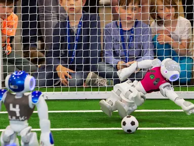 Robot penjaga gawang tim 'Nomadz' Swiss berhasil menahan bola saat melawan robot tim 'Hulk' dari Jerman dalam pertandingan kompetisi Liga Platform Standar di RoboCup GermanOpen 2018, Magdeburg, Jerman (28/4). (AP/Jens Meyer)