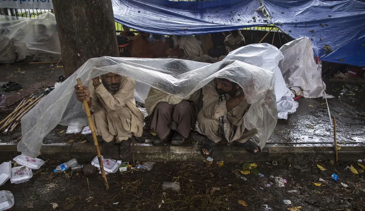Pengunjuk rasa anti-pemerintah Pakistan bernaung di bawah lembaran plastik saat hujan deras menuntut pengunduran diri Perdana Menteri Nawaz Sharif, (4/9/2014). (REUTERS/Zohra Bensemra)