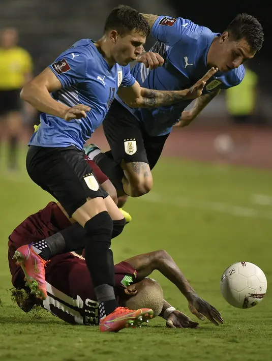 Gelandang timnas Venezuela, Romulo Otero (bawah) bersaing dengan pemain Uruguay, Giovanni Gonzalez dan Matias Vecino dalam lanjutan kualifikasi Piala Dunia 2022 di Stadion Olimpico de la UCV, Rabu (9/6/2021) pagi WIB. Uruguay ditahan imbang tanpa gol oleh Venezuela. (AP Photo/Matias Delacroix, Pool)