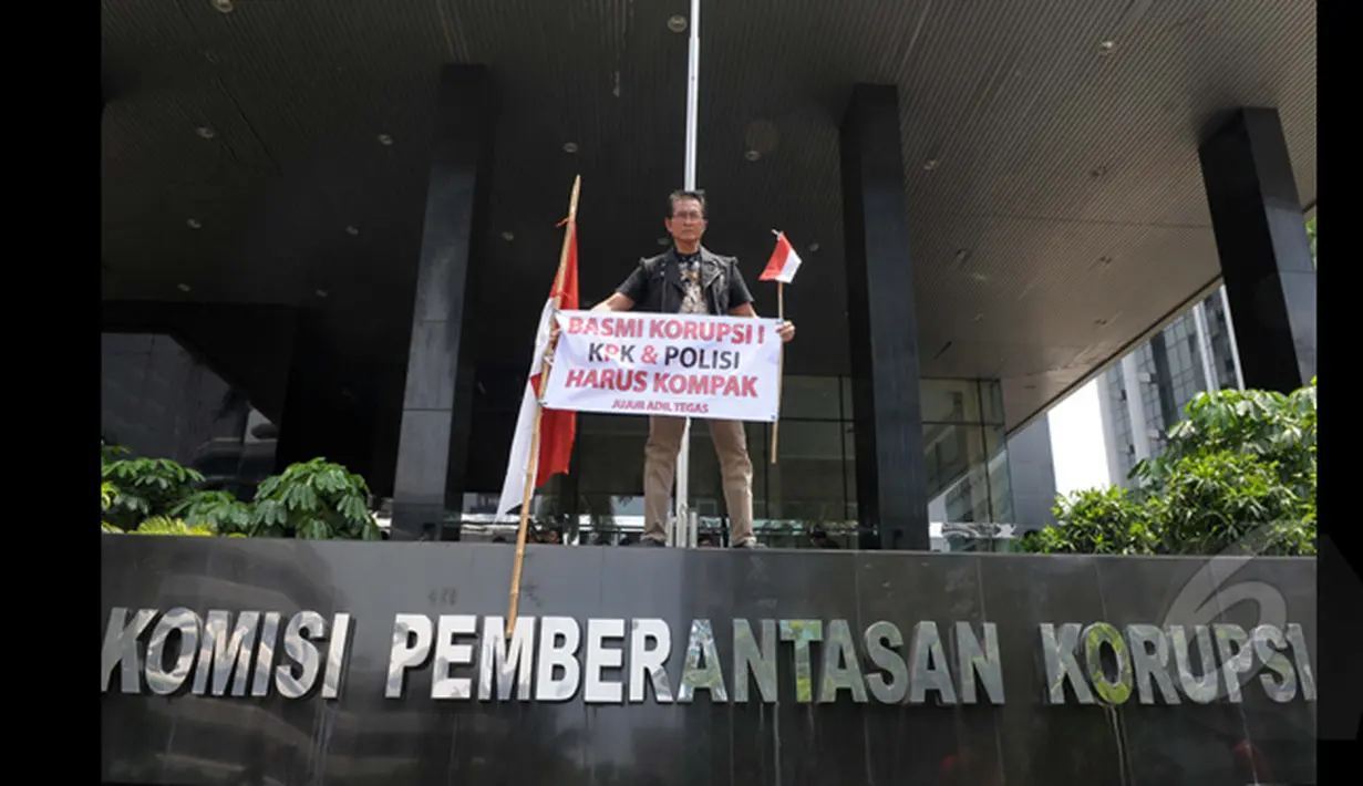 Pong Harjatmo, membentangkan spanduk di depan Gedung Komisi Pemberantasan Korupsi (KPK), Jakarta, Rabu (28/1/2015). Pong Harjatmo menyerukan agar KPK - Polri kompak untuk memberantas korupsi yang merugikan rakyat Indonesia. (Liputan6.com/Andrian M Tunay)