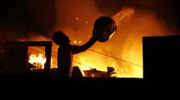 Seorang pria berusaha menyiramkan air saat kebakaran di lingkungan Educandos, di Manaus, Brasil (17/12). Kebakaran diduga disebabkan oleh ledakan panci presto yang menghanguskan ratusan rumah warga. (AP Photo/Edmar Barros)