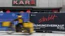 Seorang tukang pos melewati toko yang tutup di pusat kota Munich, Jerman, Selasa (23/3/2021). Jerman memperpanjang tindakan pengunciannya sebulan lagi. (AP Photo/Matthias Schrader)