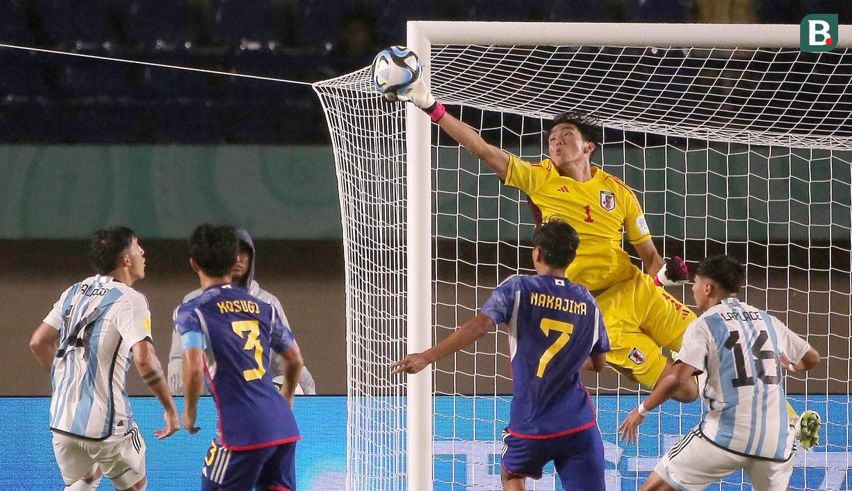 Kiper Timnas Jepang U-17, Wataru Goto (kanan atas) berhasil menghalau bola tendangan dari pemain Timnas Argentina U-17 dalam pertandingan Grup D Piala Dunia U-17 2023 yang berlangsung di Stadion Si Jalak Harupat, Selasa (14/11/2023). (Bola.com/Ikhwan Yanuar)