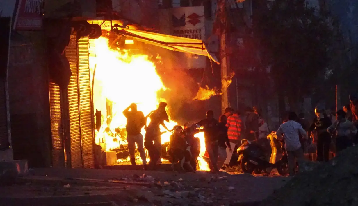 Massa membakar sebuah toko saat bentrok antara pendukung dan penentang Undang-Undang Kewarganegaraan baru di New Delhi, India, Selasa (25/2/2020). Bentrokan menewaskan 15 orang dan melukai ratusan lainnya. (AP Photo)