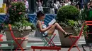 Seorang wanita membaca buku di bawah sinar matahari pada hari yang hangat di New York City (7/6/2021). Cuaca yang hangat di New York dimanfaatkan warga untuk membaca buku hingga berjalan-jalan. (AFP/Angela Weiss)