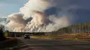 Sebuah mobil berjalan melintas berada tak jauh dari kepulan asap yang membakar hutan di wilayah Fort McMurray, Alberta, Kanda, 4 Mei 2016. Sekitar 80 ribu warga Kanada terpaksa dievakuasi Akibat kebakaran dahsyat ini. (REUTERS / Mark Blinch)