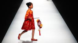 Seorang anak berjalan di atas catwalk membawakan karya desainer Amelie Wang pada China Fashion Week di Beijing,  31 Oktober 2017. (AP Photo/Andy Wong)