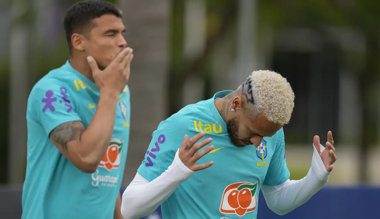 Penyerang Brasil Neymar dan bek Thiago Silva memasuki lapangan untuk sesi latihan tim di Sao Paulo, Brasil, Rabu (10/11/2021).  Neymar menghiasi barnetnya yang diputihkan dengan semprotan hitam dalam bentuk logo Batman yang ikonik. (AP Photo/Andre Penner)