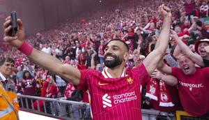 Pemain Liverpool, Mohamed Salah merayakan kemenangan dengan berswafoto bersama dengan para suporter timnya dalam laga lanjutan Liga Inggris 2024/2025 melawan Tottenham Hotspur di Anfiled, Liverpool, Inggris, Minggu (27/04/2025) waktu setempat. (AP Photo/Jon Super)
