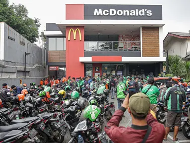 Kerumunan pengemudi ojek online saat antre mengambil pesanan di gerai cepat saji McDonald's Raden Saleh, Jakarta, Rabu (9/6/2021). Puluhan driver ojek online terlihat mengabaikan protokol kesehatan saat mengantre pesanan BTS Meal yang mulai dijual. (Liputan6.com/Faizal Fanani)